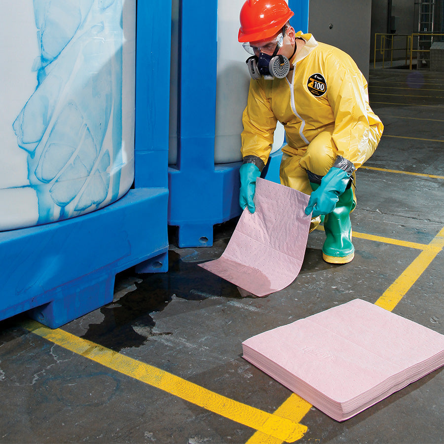 Chemische lekkage op de werkvloer welke wordt geabsorbeert door werknemer met roze absorptiedoeken