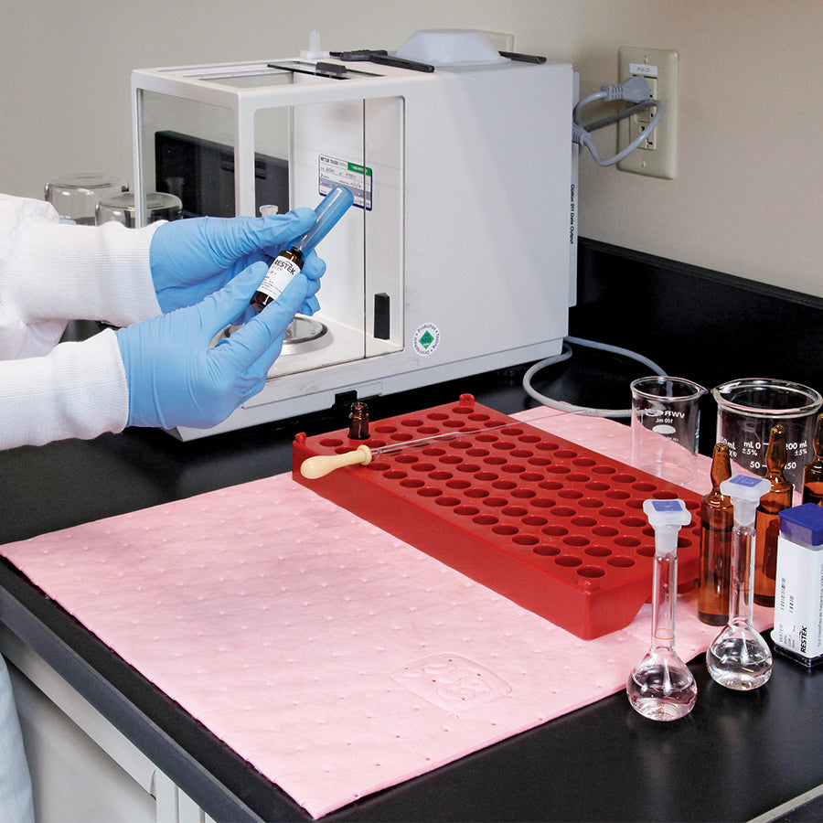 Roze absorptiedoek voor chemie liggend op werkbank laboratorium onder reageerbuis, pipetten