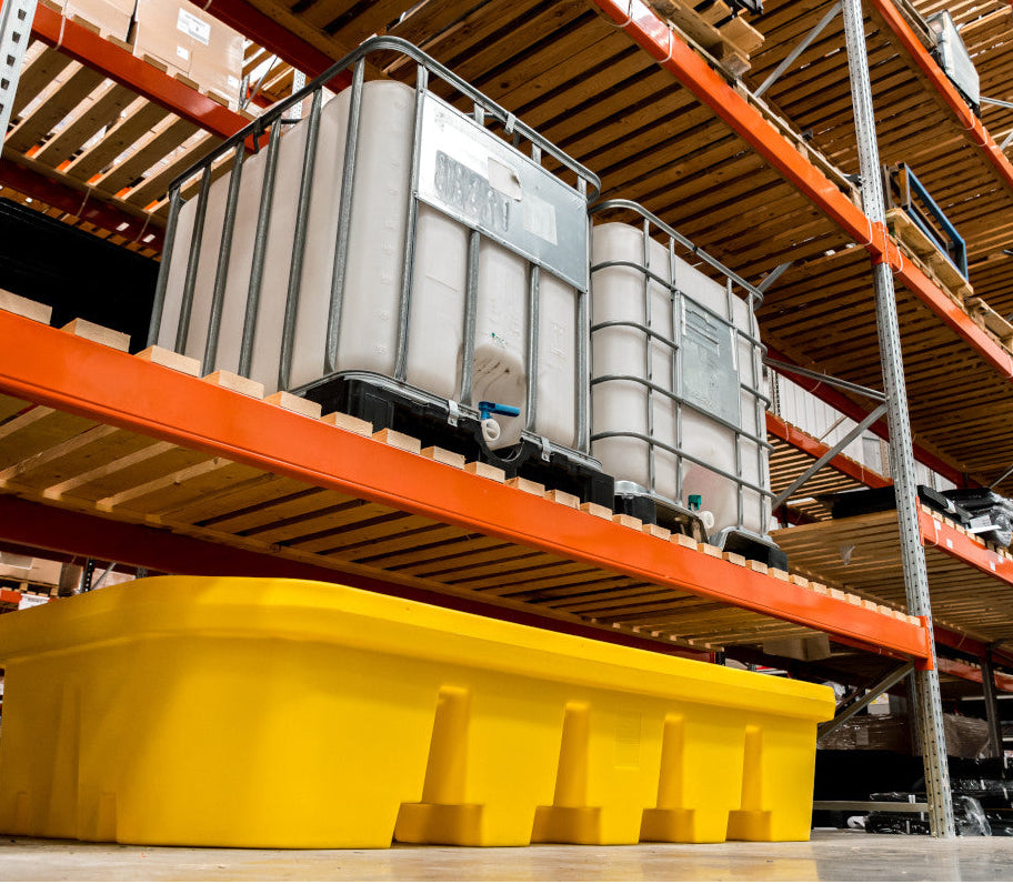 Gele lekbak onder palletrek in een magazijn, geplaatst onder een palletrek met een IBC-container op het rek