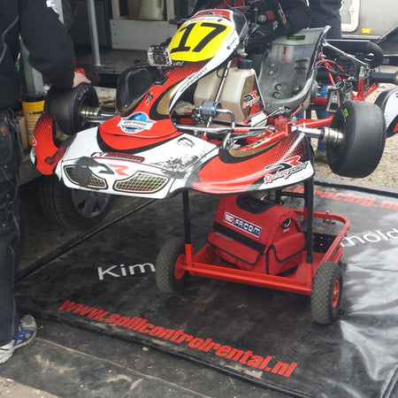 kart die op een lekmat staat in de paddock om olie en brandstof op te vangen, te koop bij absorptieshop