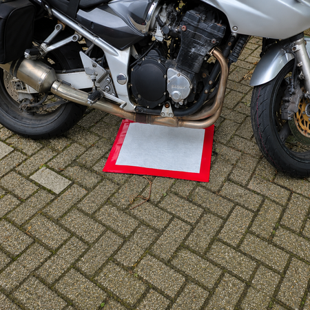 Motoren lekken olie op de stoep waar deze gepakeerd staat, de lekmat vangt de olie op, Absorptieshop.