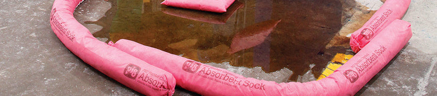 Roze absorberende chemische sokken toegepast op de werkvloer om een lekkage in te dammen