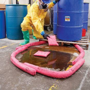 Lekkages chemische vloeistof op de werkvloer uit een vat ingedams met roze absorberende sokken en kussens