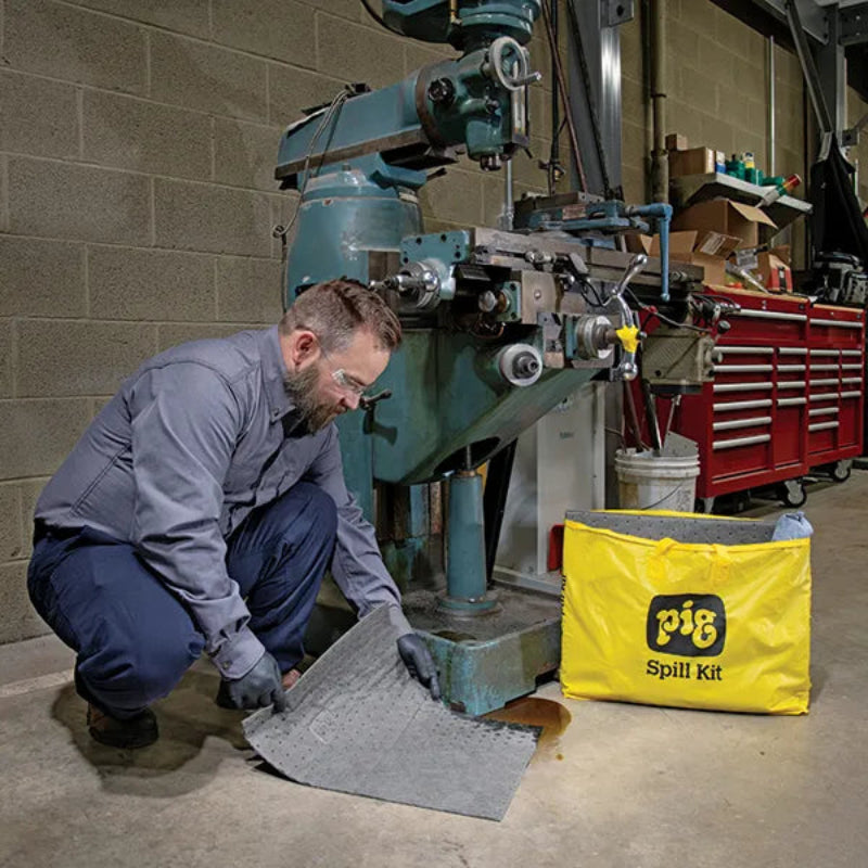 Monteur gebruikt de absorberende mat uit de universele spill kit van absorptieshop na olielekkage in de werkplaats